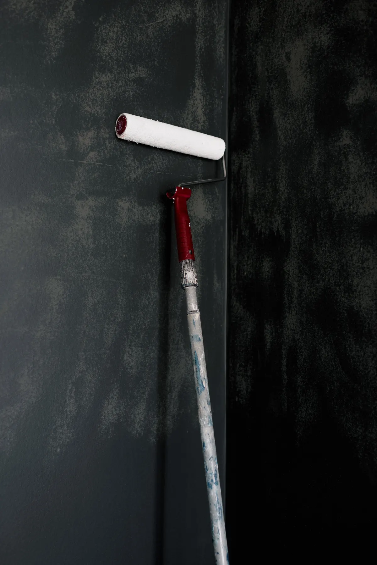 Paint roller against a dark interior wall during renovation